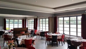 A spacious dining area with multiple tables and chairs, large windows, and a grand piano. - Hotel Restaurant du Lac (Boe)