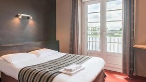 A hotel room with a bed, a window with a view, and a wall-mounted light fixture. - Hotel Restaurant du Lac (Boe)