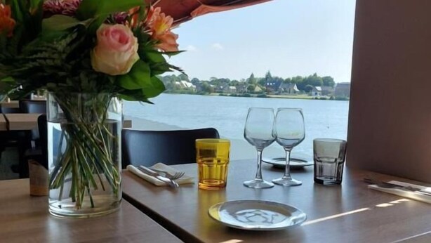 A dining table with a vase of flowers, a yellow glass, and wine glasses. - Hotel Restaurant du Lac (Boe)