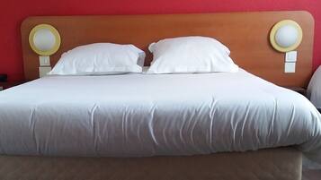 A bed with white bedding, wooden headboard, and two bedside lamps.
