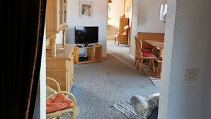 A cozy living room with a television, wooden furniture, and a dining area. - Ferienhaus Haidweg (Haidmuhle)