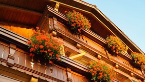 A multi-story building with wooden balconies adorned with red flowers. - Ferienhaus Haidweg (Haidmuhle)