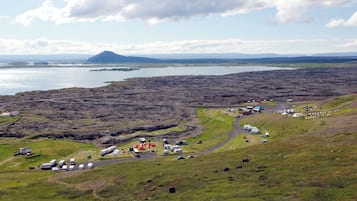 A campsite with RVs and tents, a dirt road, and a mountain in the background.