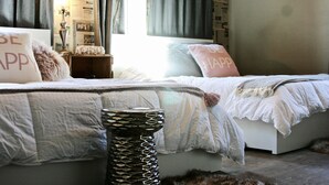 Un dormitorio con dos camas, una mesita de noche y un jarrón decorativo.