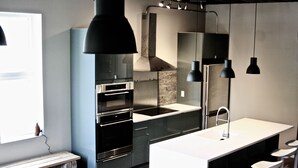 Una cocina moderna con una isla central, horno empotrado y un ventanal grande.
