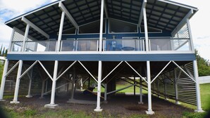 A two-story building with a covered upper level and a lower level with a balcony. - Big Private Mt. Home Minutes to Volcanos National Park
Myra's Blue Hawaii House  (Ocean View)