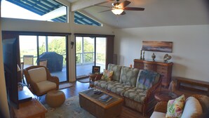 A spacious living room with a large sofa, a television, and a ceiling fan. - Big Private Mt. Home Minutes to Volcanos National Park
Myra's Blue Hawaii House  (Ocean View)
