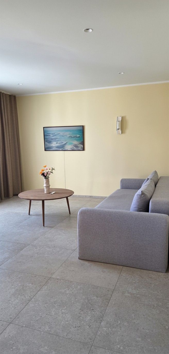 Un salón moderno con un sofá gris, una mesa de centro redonda y un cuadro en la pared.