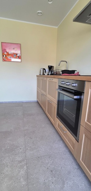A kitchen with a built-in oven, a sink, and a countertop with a kettle and coffee maker. - Eldá apartments (Myvatn)