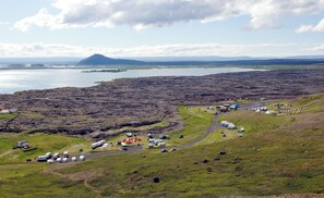 A campsite with RVs and tents, a road, and a distant mountain. - Eldá apartments (Myvatn)
