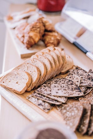 A variety of sliced bread and crackers on a wooden board. - Eldá apartments (Myvatn)