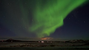 A night sky with the Northern Lights over a barren landscape. - Eldá apartments (Myvatn)