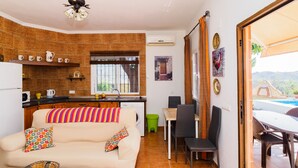 Ein kompakter Wohnraum mit Küchenzeile, Essbereich und einer Couch mit bunter Decke.