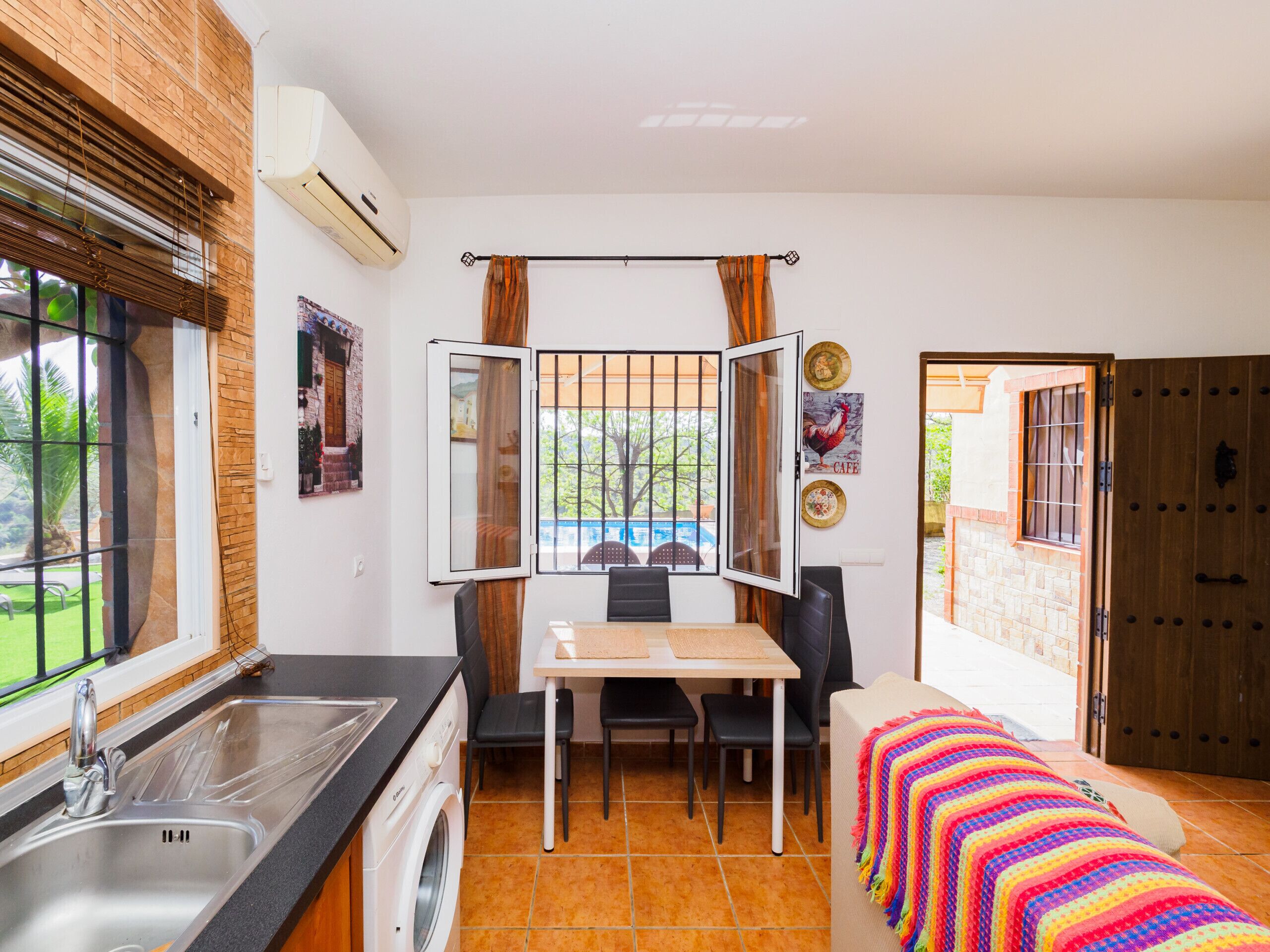 A compact kitchen with a sink, a washing machine, and a dining area with a table and chairs.