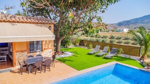 Ein Wohnhaus mit Schwimmbad, einer Terrasse mit Sitzgelegenheiten, einem Rasen und Blick auf Hügel.