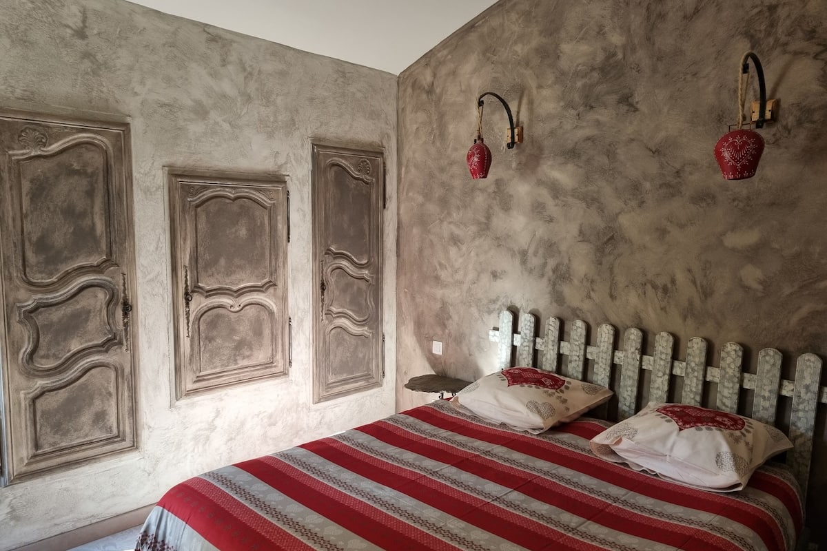 Une chambre à coucher avec un lit, deux lampes fixées au mur et un mur à texture.