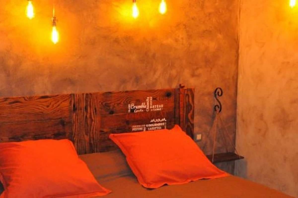 Une chambre à coucher avec une tête de lit en bois, deux oreillers orange et un lit.