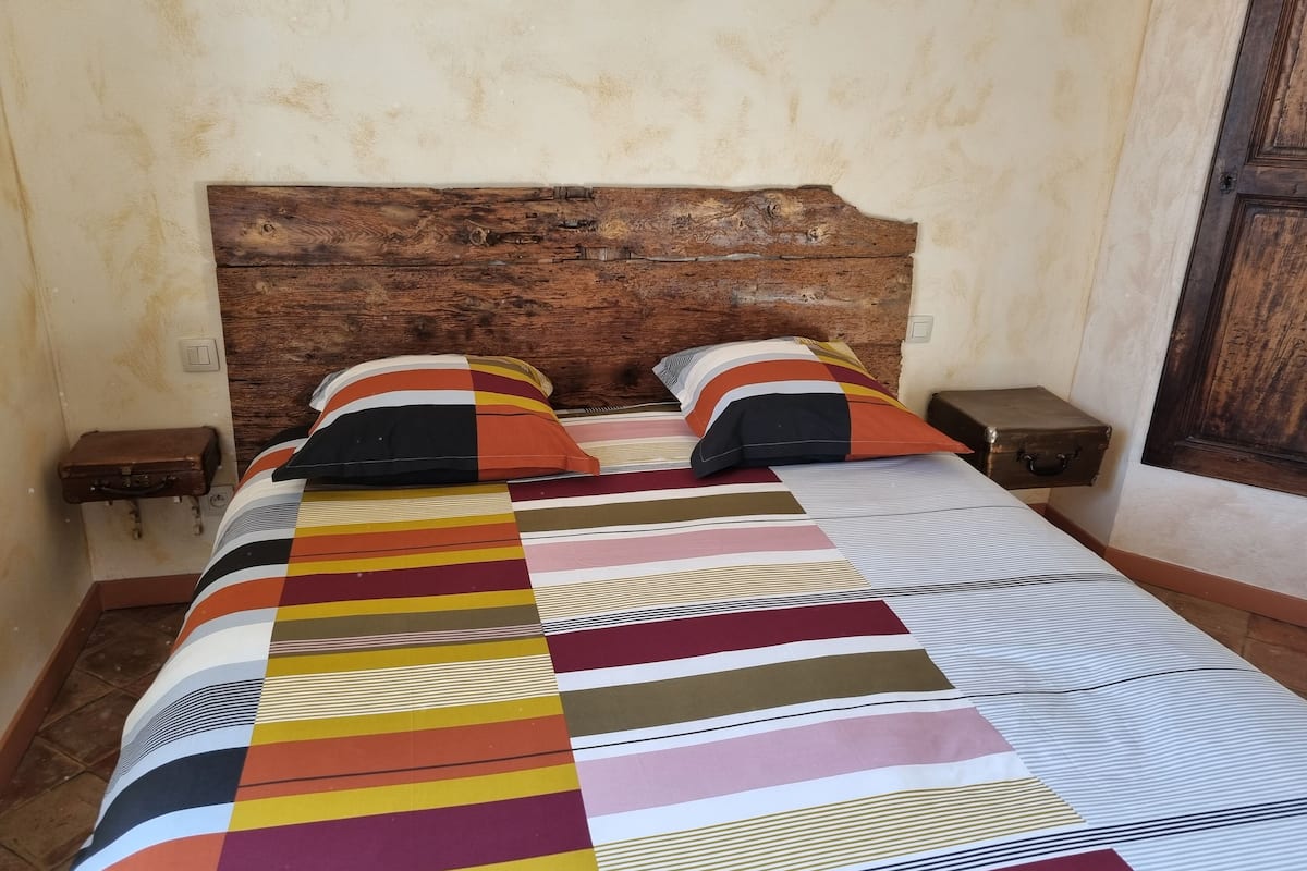 Un lit avec une couvre-lit à rayures, deux oreillers et deux tables de chevet avec des lampes.