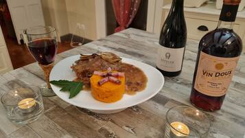A table with a plate of food, two wine bottles, and two glasses of wine.