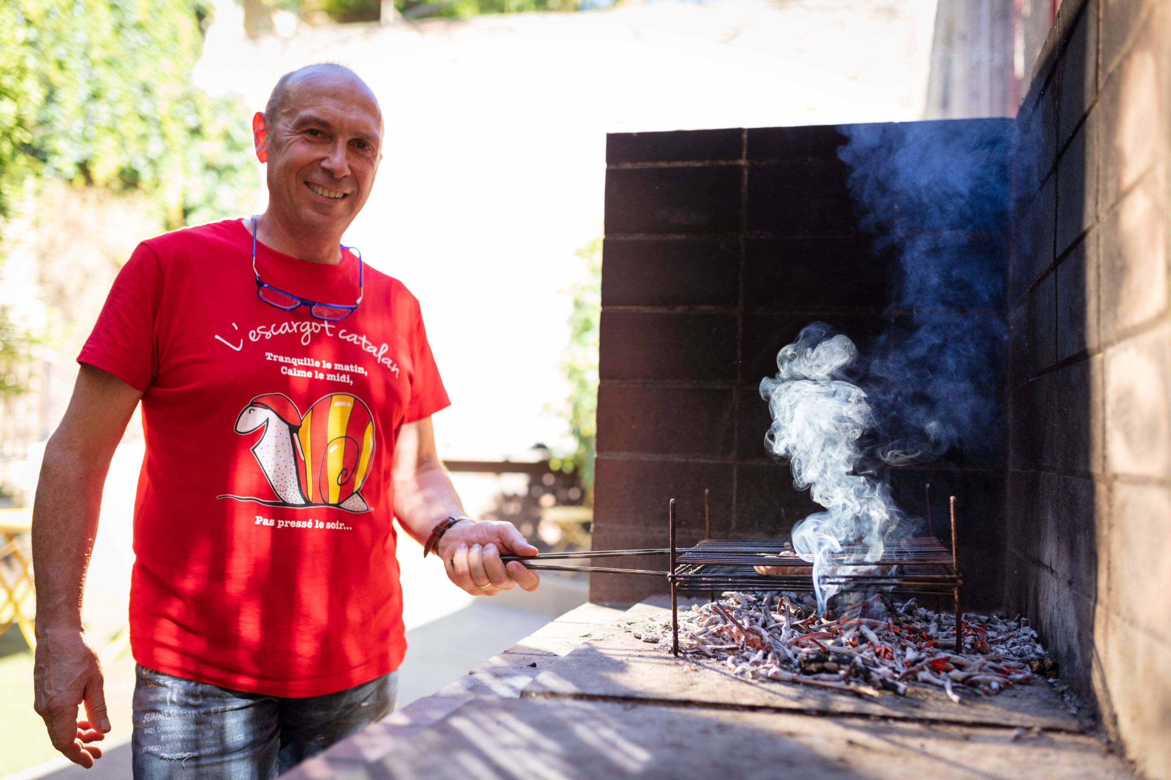 A man grilling outdoors with a visible smoke stack.