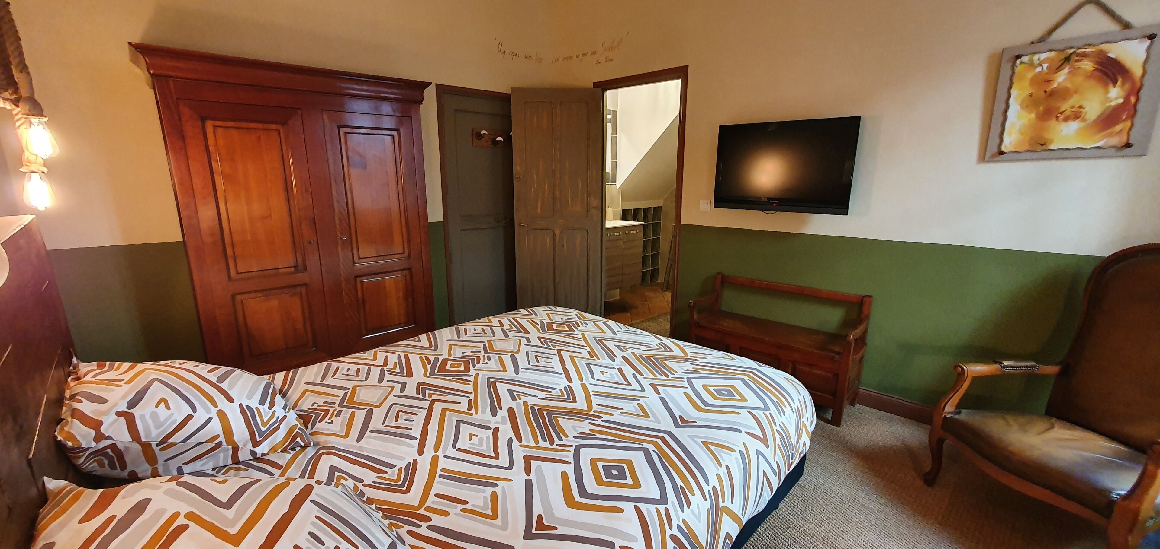 Une chambre à coucher avec un lit, une chaise, une télévision et une armoire.