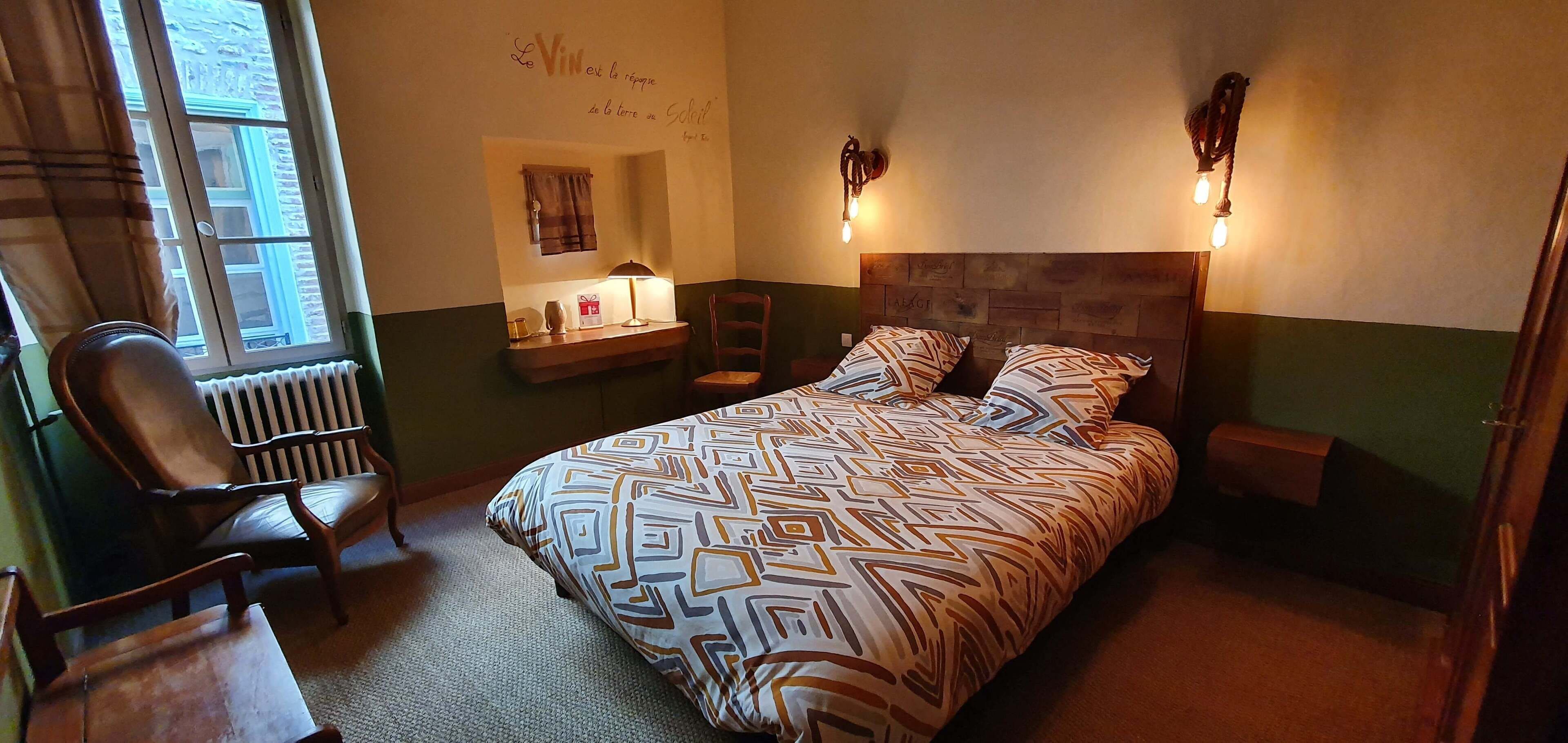 Een slaapkamer met een bed, twee bedlampen, een stoel, een bureau, een radiator en een raam met gordijnen.