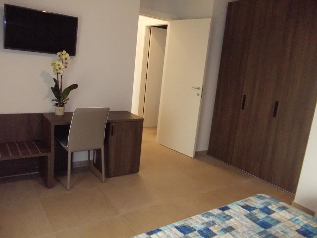 Une chambre à coucher comprenant un lit, un bureau, une chaise, une télévision, une armoire et une porte.