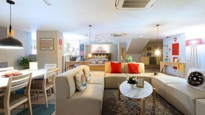 A modern living room with a sofa, coffee table, and dining area. - Yeah Barcelona Hostel (Barcelona)