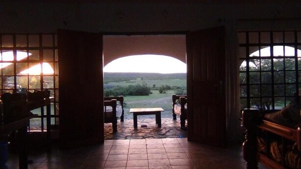 Een kamer met uitzicht op een landschap door een open boog.