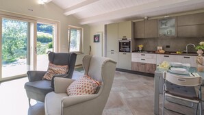 Une cuisine moderne avec un coin repas, comprenant un canapé agrémenté de coussins à motifs, une table à manger avec des chaises, et une vue sur la verdure à l’extérieur.