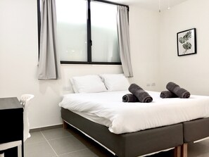 A bedroom with a bed, a desk, and a window with curtains. - Old Jaffa Designers House (Tel Aviv)