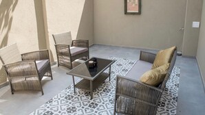 A patio with wicker furniture, a tiled floor, and a framed notice on the wall. - Old Jaffa Designers House (Tel Aviv)