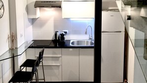 A modern kitchen with white cabinets, a stainless steel sink, a black countertop, and a hanging light fixture. - Old Jaffa Designers House (Tel Aviv)