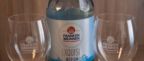Una bottiglia di Franken Brunnen Exquisiti Medium con due bicchieri vuoti su un ripiano di legno.