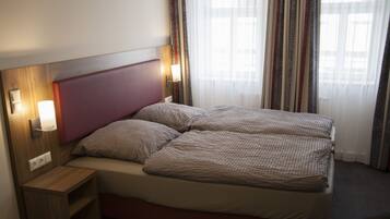 Een tweepersoonsbed met een houten hoofdbord, twee nachtkastjes en een bijzettafeltje.