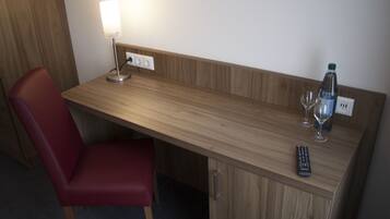 Uma mesa de madeira com uma luminária, um controle remoto e uma garrafa de água.