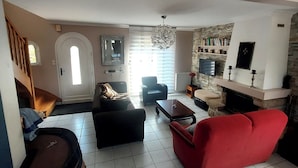 A living room with a red sofa, a wooden coffee table, a fireplace, and a stone wall.
