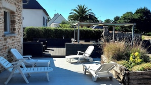 A patio area with lounge chairs, a barbecue grill, and a pergola.