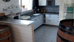 A modern kitchen with a central island, white cabinets, a black backsplash, and a large wall clock.