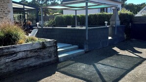 A covered outdoor area with a stone wall, a small water feature, and a pergola.