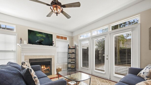 A living room with a fireplace, a ceiling fan, and a large window with blinds. - Lions Bridge: Modern 3 bedroom Home in Historic Lincolnville - walk to Historic (St. Augustine)