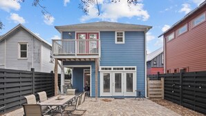 A two-story house with a covered patio area featuring a table and chairs. - Lions Bridge: Modern 3 bedroom Home in Historic Lincolnville - walk to Historic (St. Augustine)