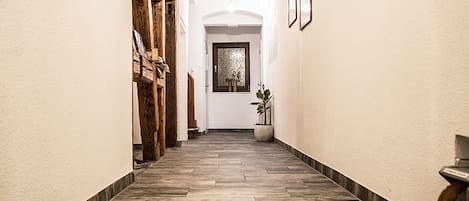 A hallway with a wooden floor, a potted plant, and a door with a frosted glass window.