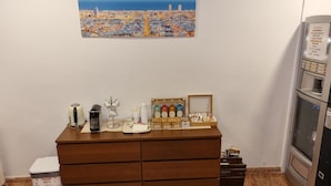 Eine Küchenzeile mit Kaffeemaschine, Wasserkocher, Kaffee- und Milchspender auf einem Holzkabinett.