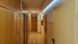 Ein Flur mit Holztüren, einem an der Wand befestigten Feuerlöscher und einem Teppichboden.