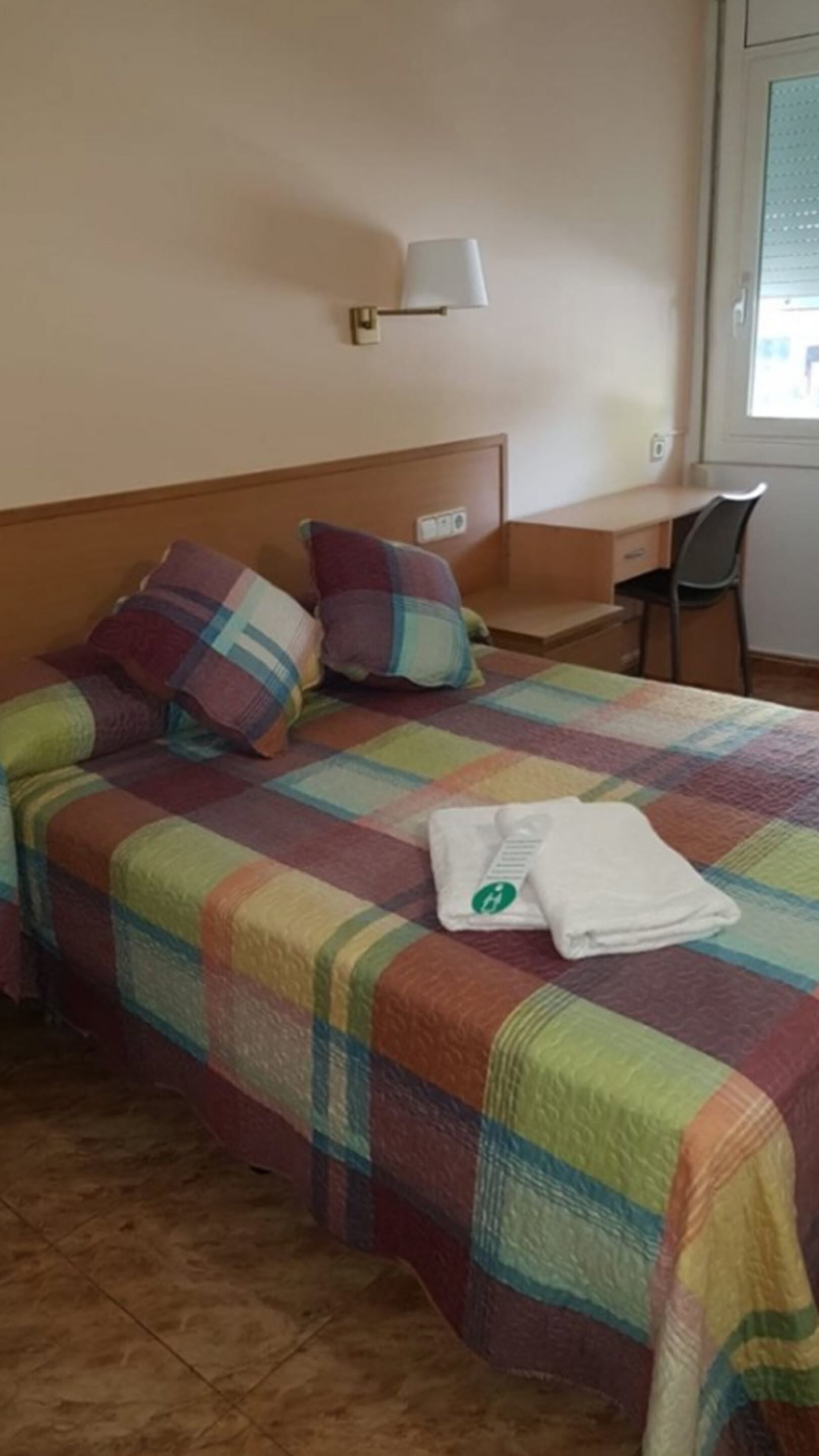Hotellihuone, jossa on sänky, työpöytä ja tuoli.