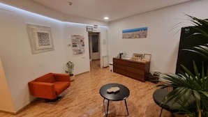 Eine Hotelhalle mit einer roten Couch, einem kleinen runden Tisch, einer Holzkommode und einem Blumentopf.