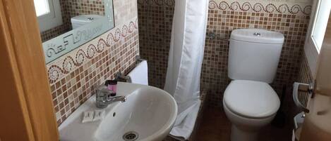 Un baño con lavamanos, inodoro y ducha.