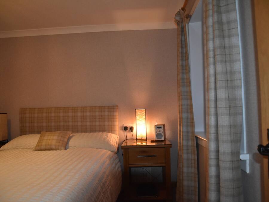 Et hotelværelse med seng, sengebord, lampe og gardiner.