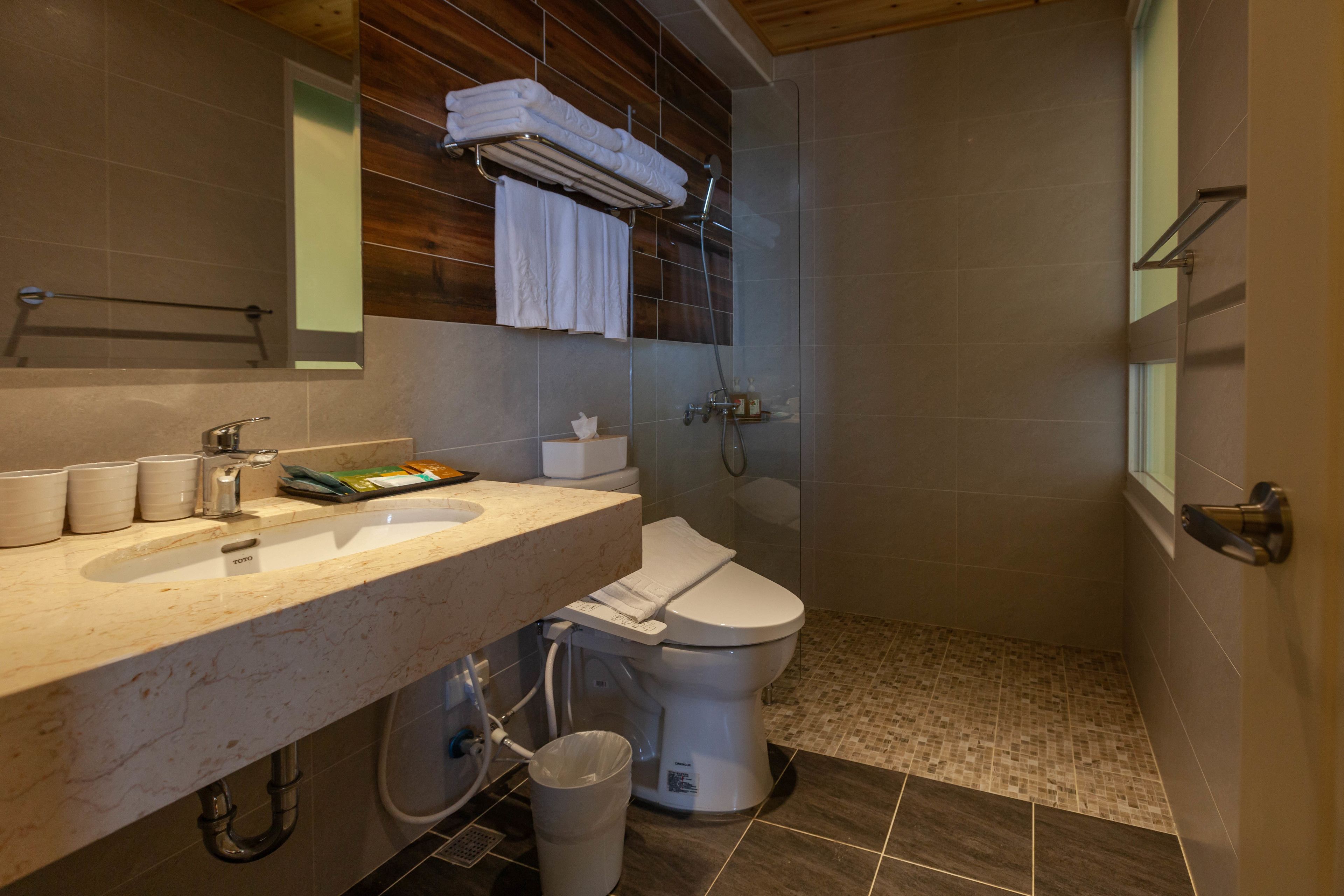Un baño moderno con lavamanos de mármol, inodoro y zona de ducha.